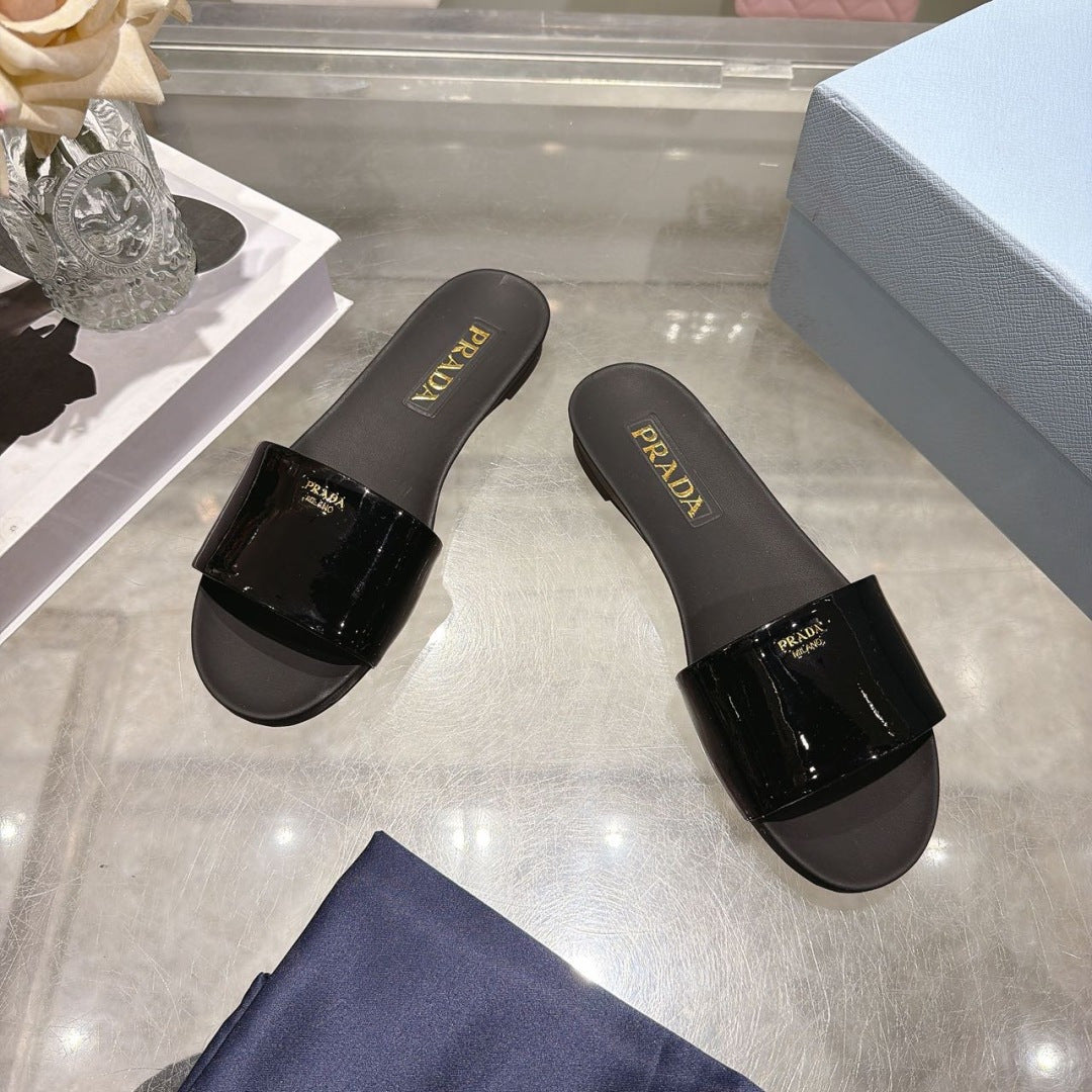PRADA 26S LOGO EMBOSSED SLIDE SANDALS IN BLACK PATENT CALFSKIN