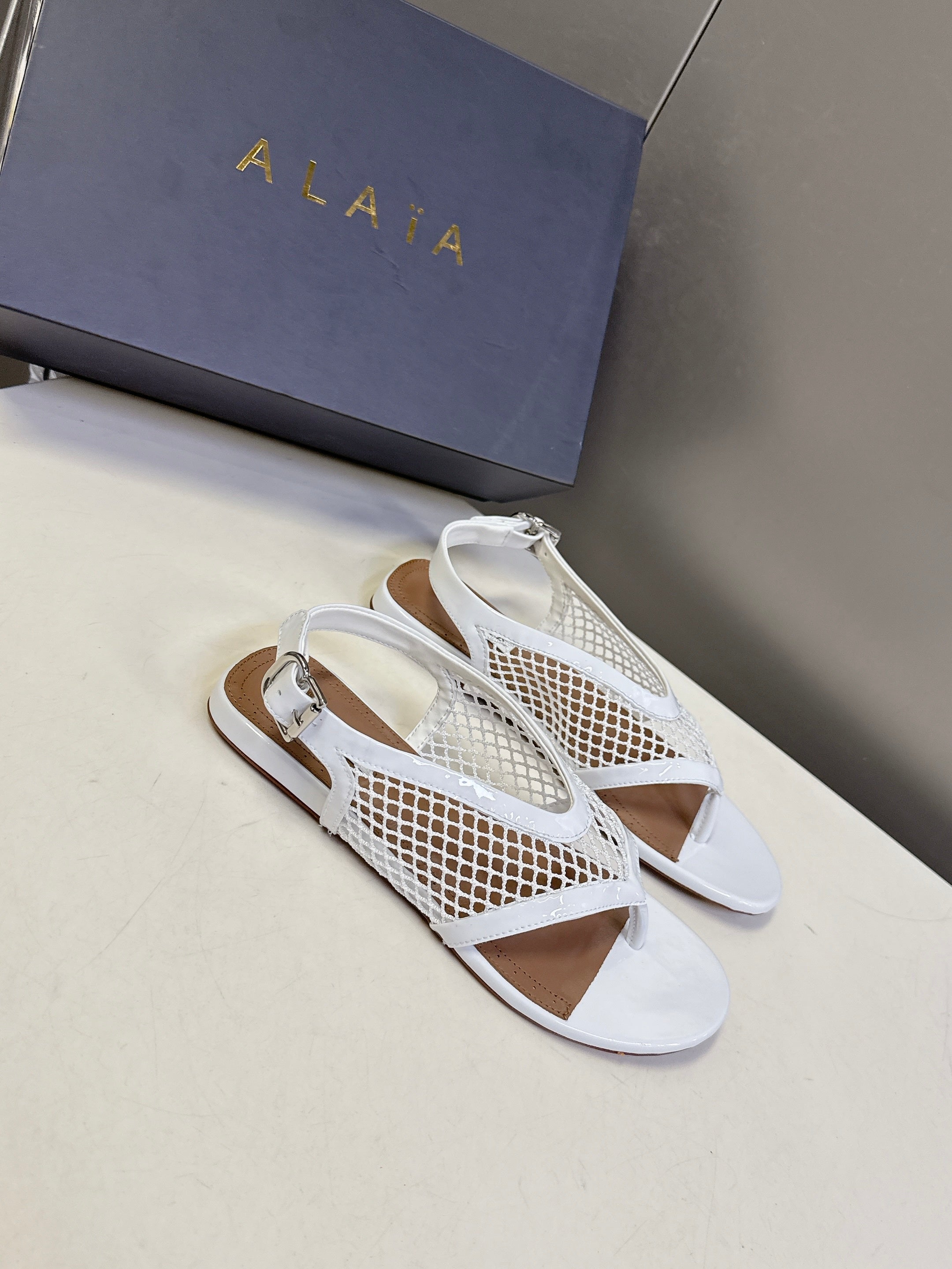 ALAIA 26S FLAT MESH THONG SANDALS IN WHITE PATENT CALFSKIN