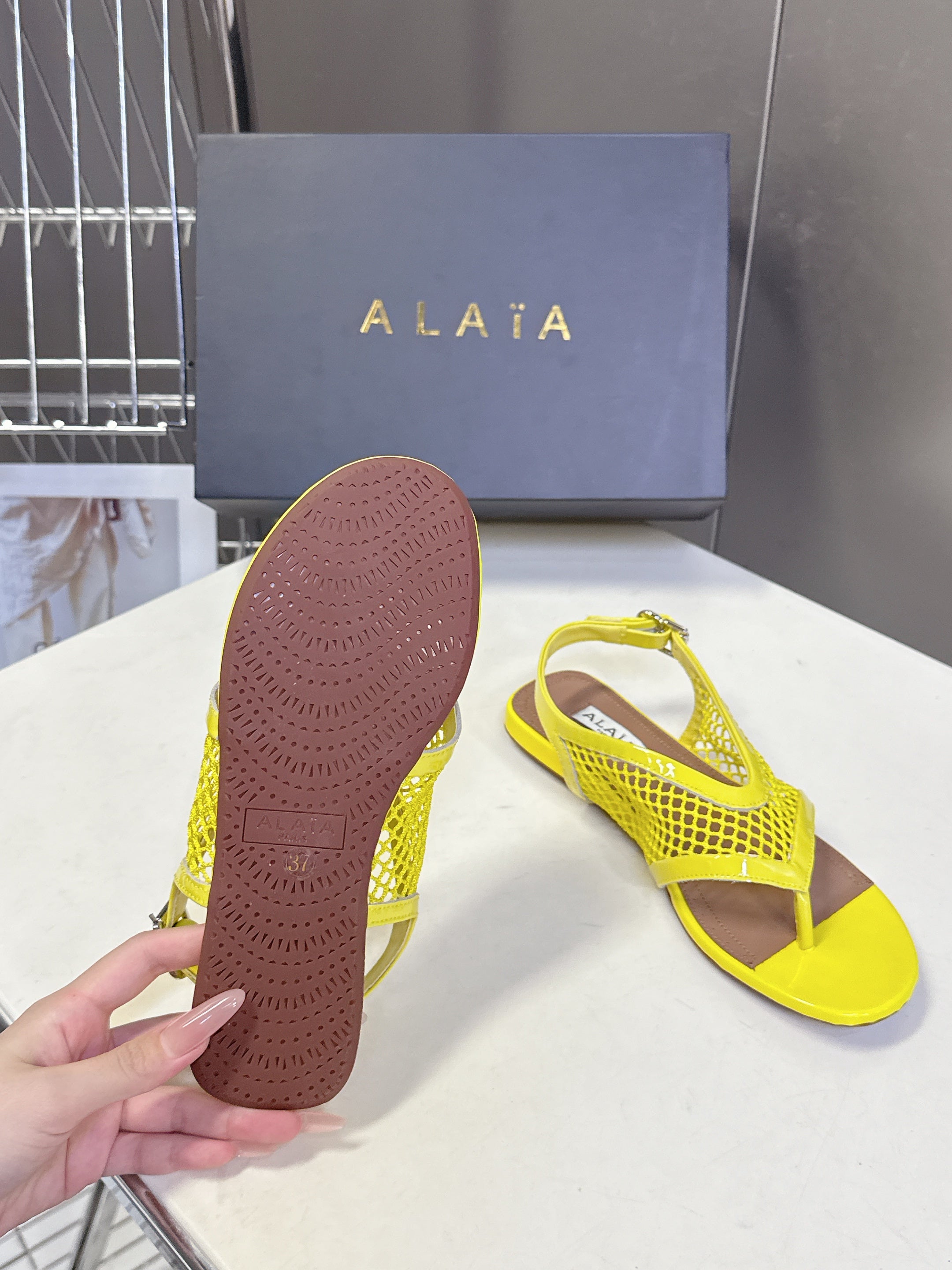 ALAIA 26S FLAT MESH THONG SANDALS IN YELLOW PATENT CALFSKIN
