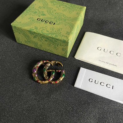 GUCCI 26S INTERLOCKING G MULTICOLOR GEM LOGO BROOCH IN ANTIQUE GOLD TONE METAL 625634