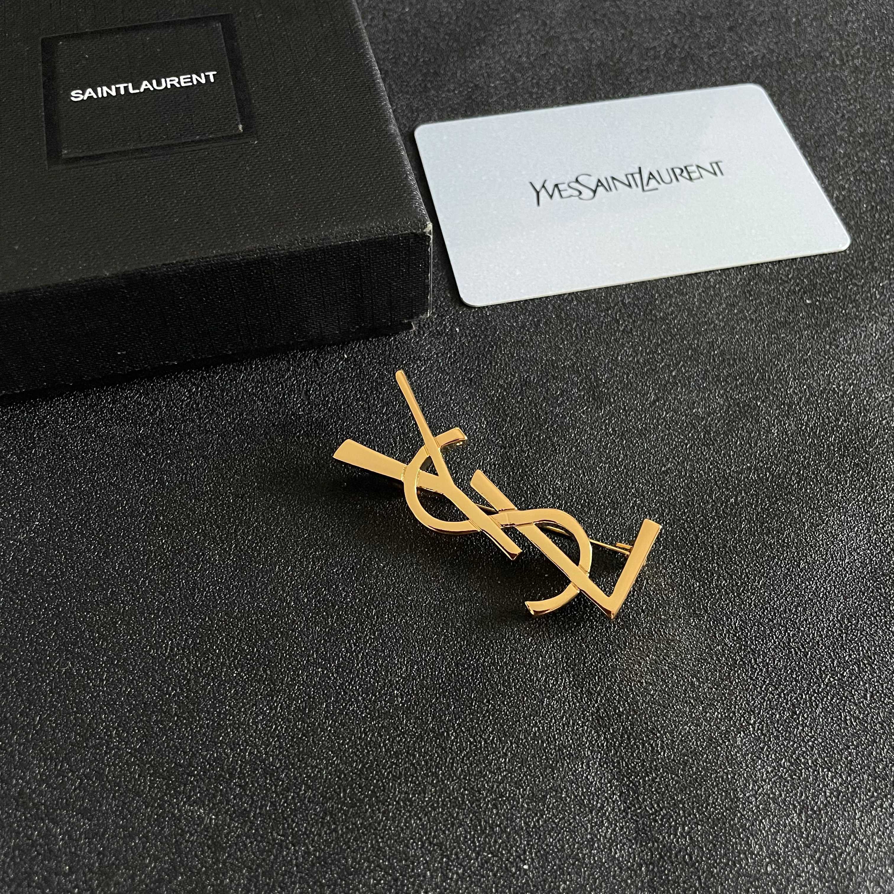 YSL 26S MONOGRAM BROOCH IN GOLD TONE METAL 630942