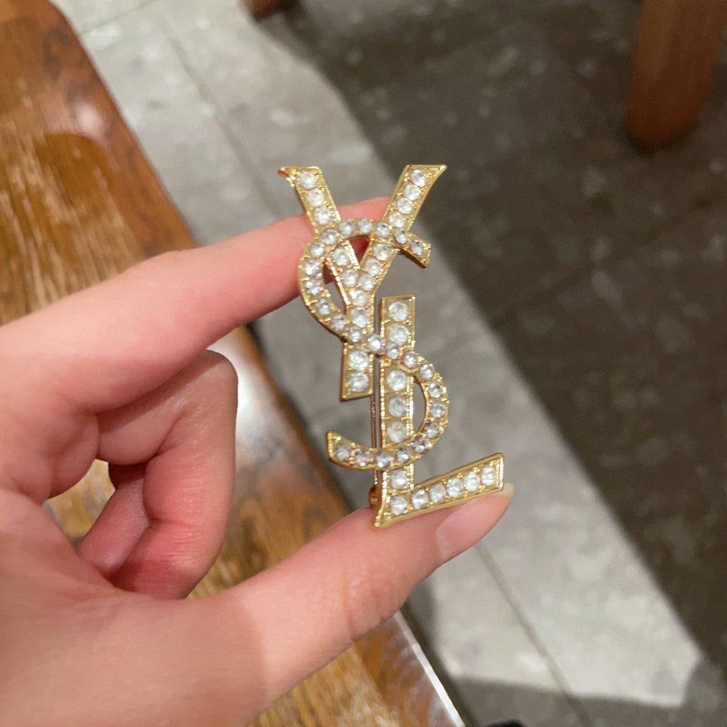 YSL 26S CRYSTAL MONOGRAM BROOCH IN GOLD TONE METAL 631043