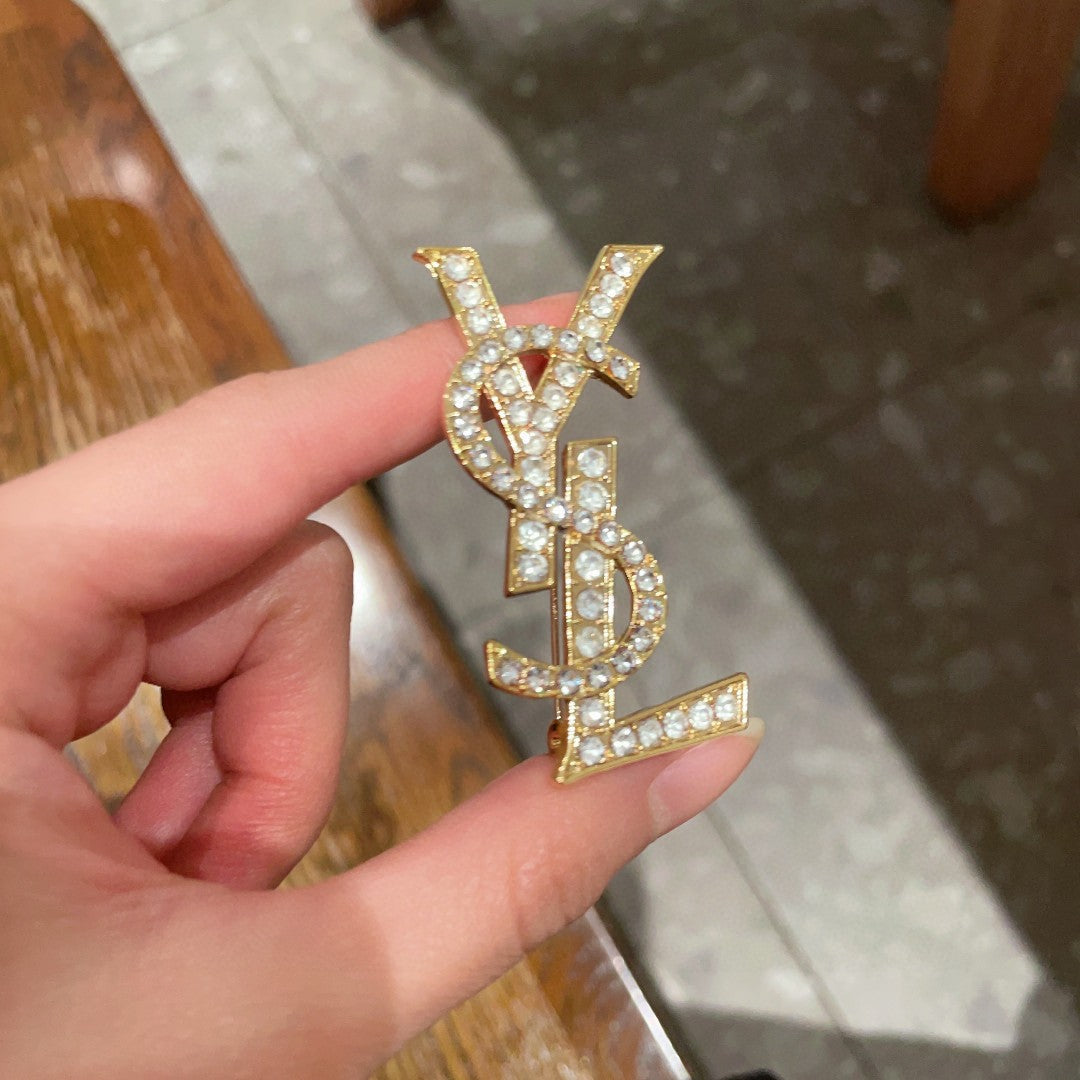 YSL 26S CRYSTAL MONOGRAM BROOCH IN GOLD TONE METAL 631043