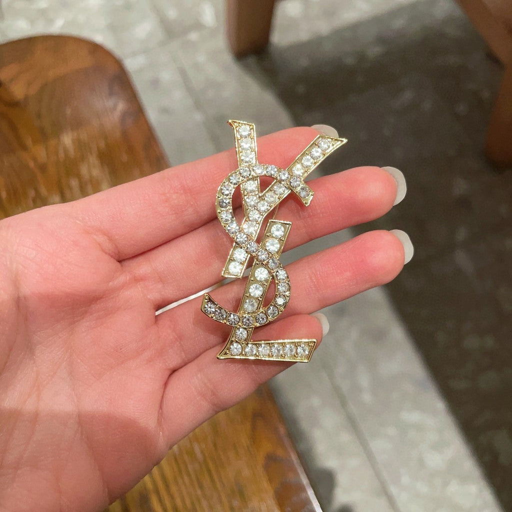 YSL 26S CRYSTAL MONOGRAM BROOCH IN GOLD TONE METAL 631043