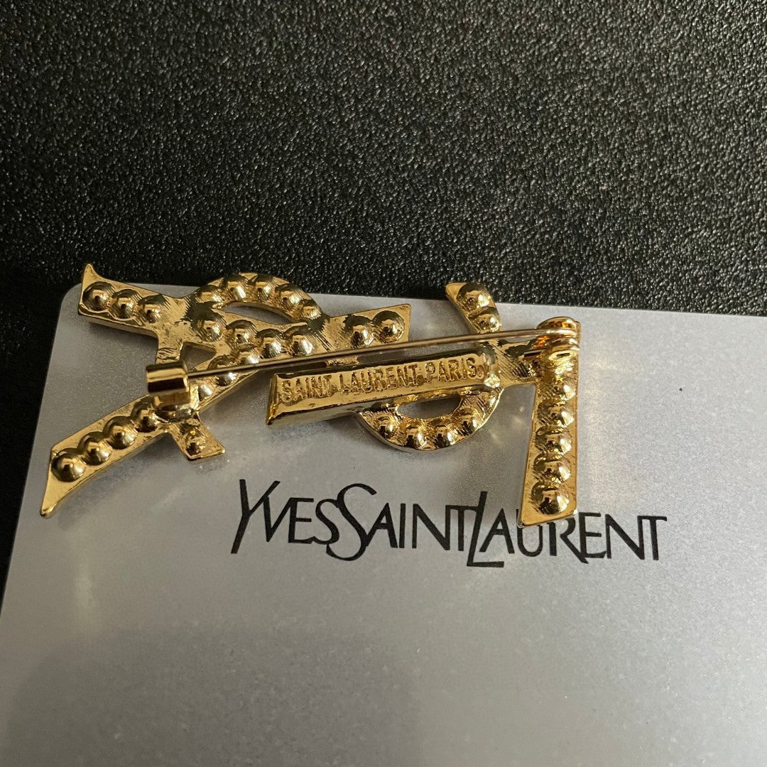 YSL 26S CRYSTAL MONOGRAM BROOCH IN GOLD TONE METAL 631043