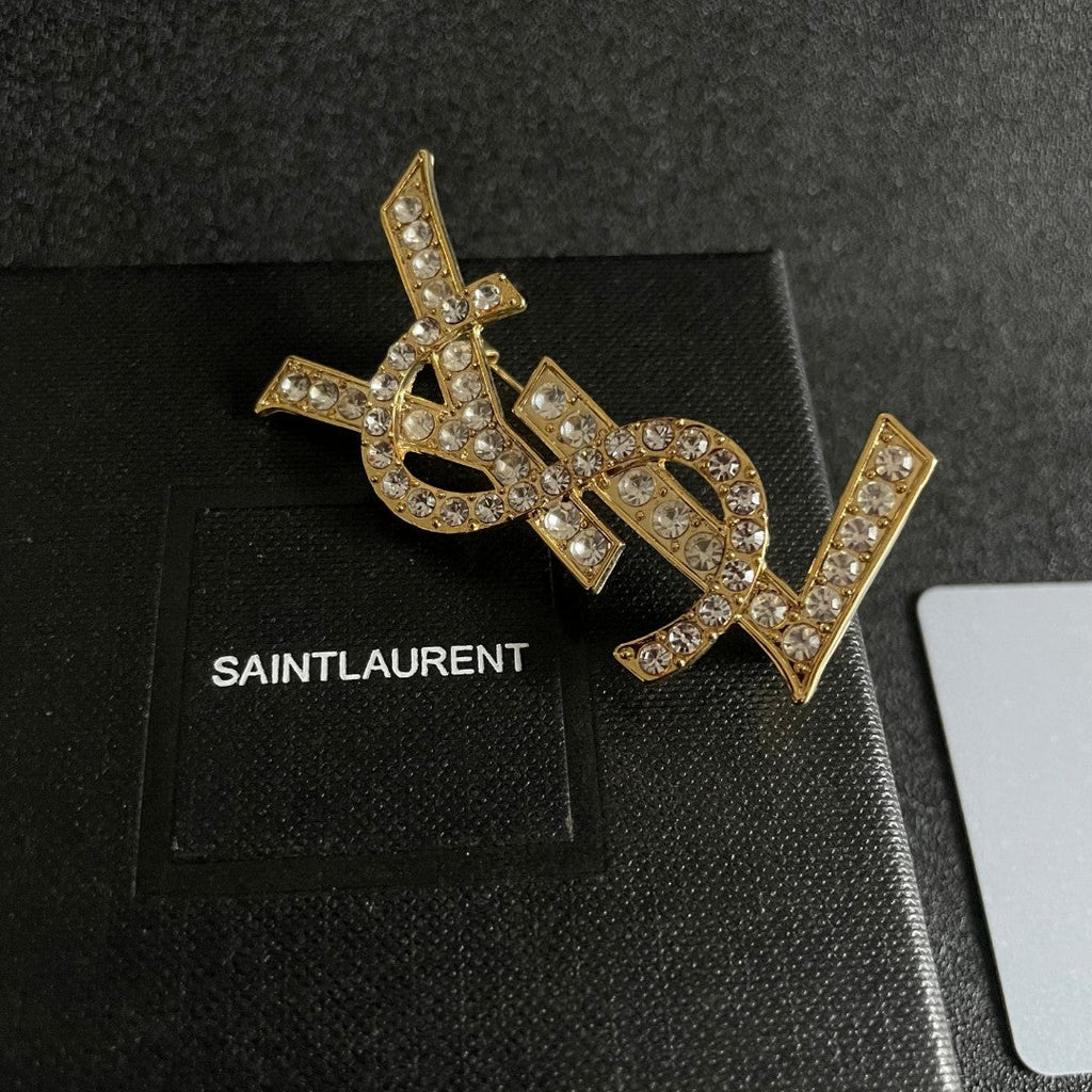 YSL 26S CRYSTAL MONOGRAM BROOCH IN GOLD TONE METAL 631043