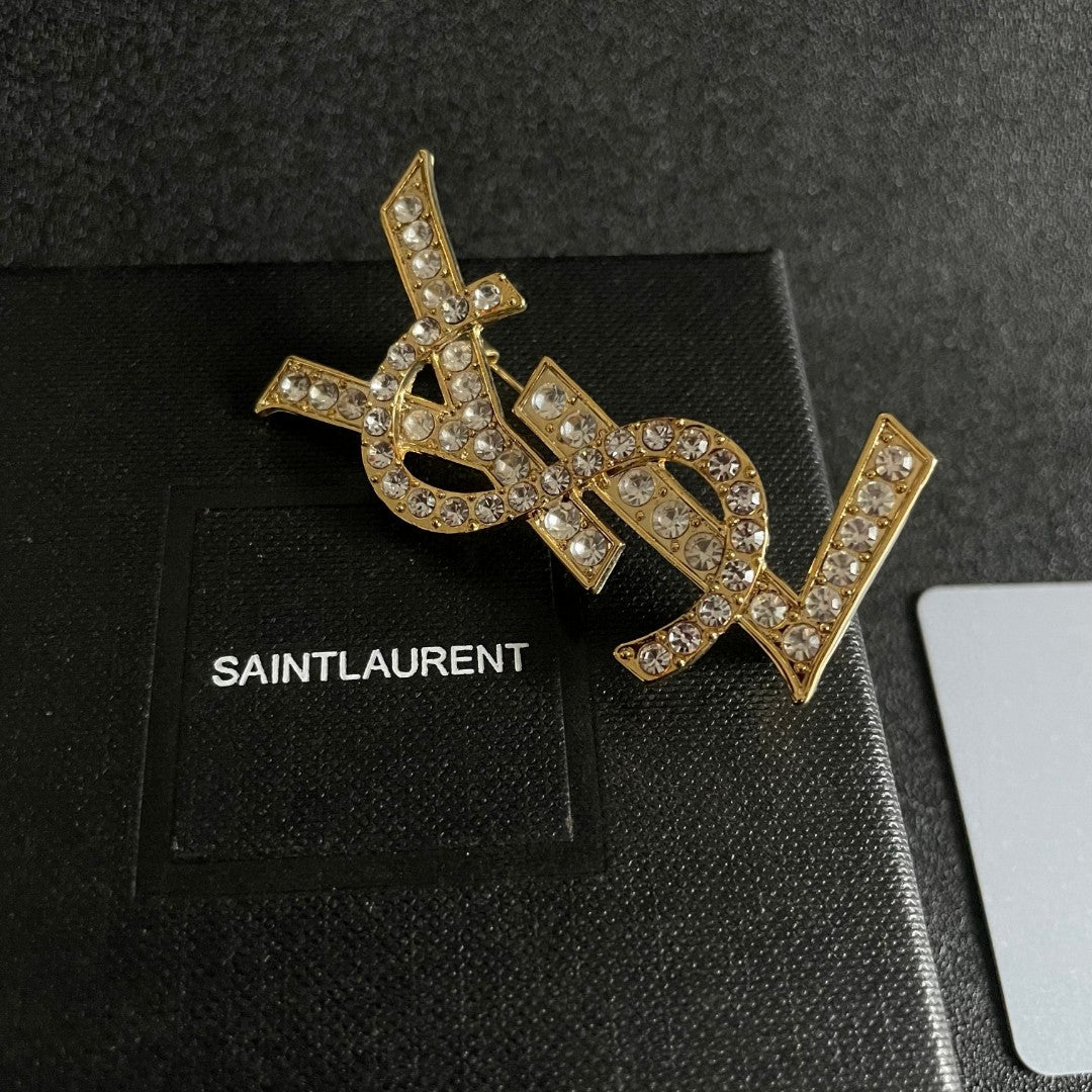 YSL 26S CRYSTAL MONOGRAM BROOCH IN GOLD TONE METAL 631043