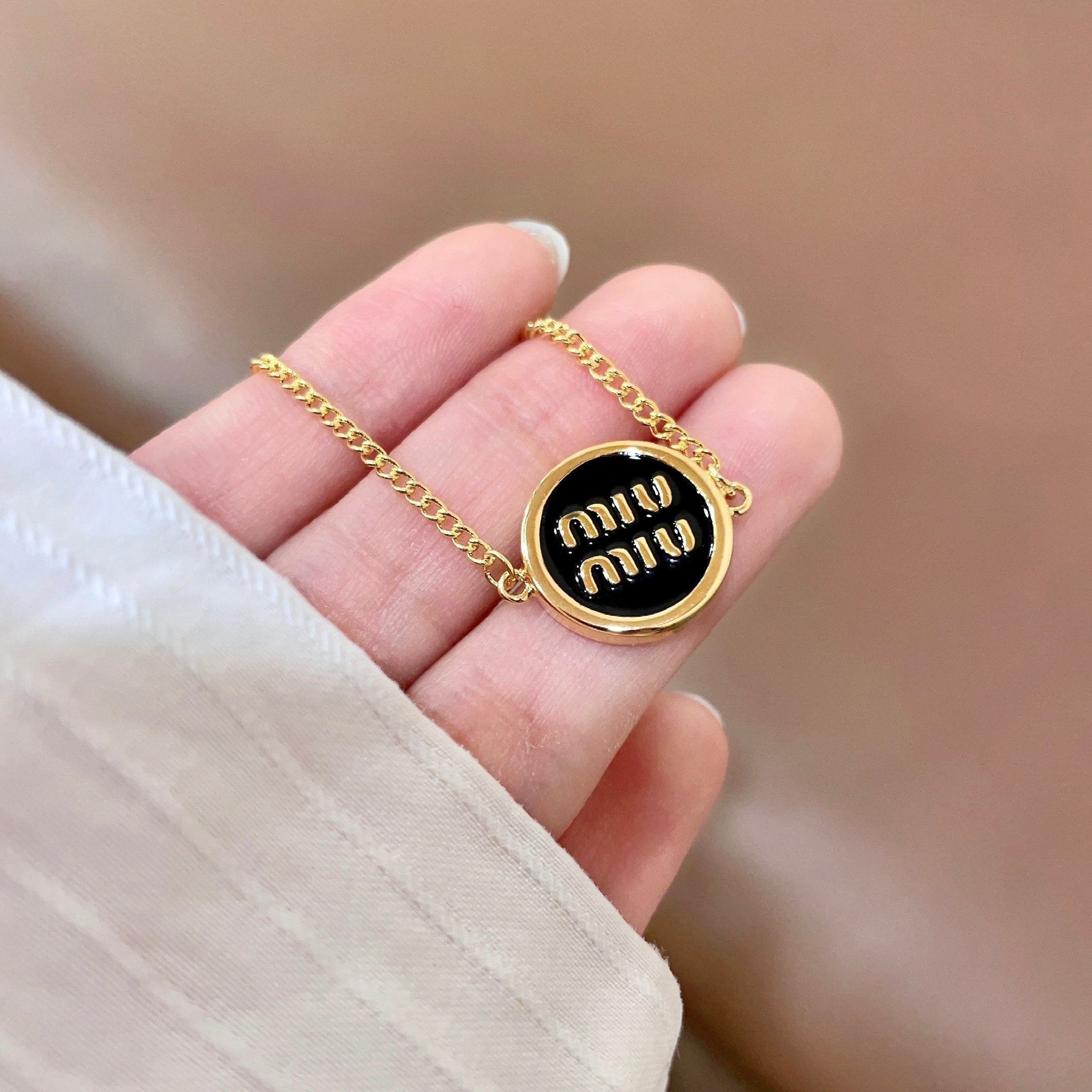 MIUMIU 26S LOGO ROUND BRACELET IN BLACK ENAMEL AND GOLD TONE METAL 631809