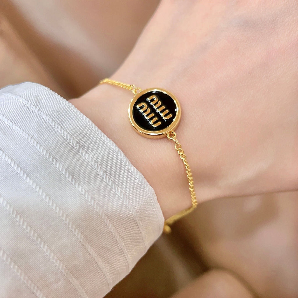 MIUMIU 26S LOGO ROUND BRACELET IN BLACK ENAMEL AND GOLD TONE METAL 631809