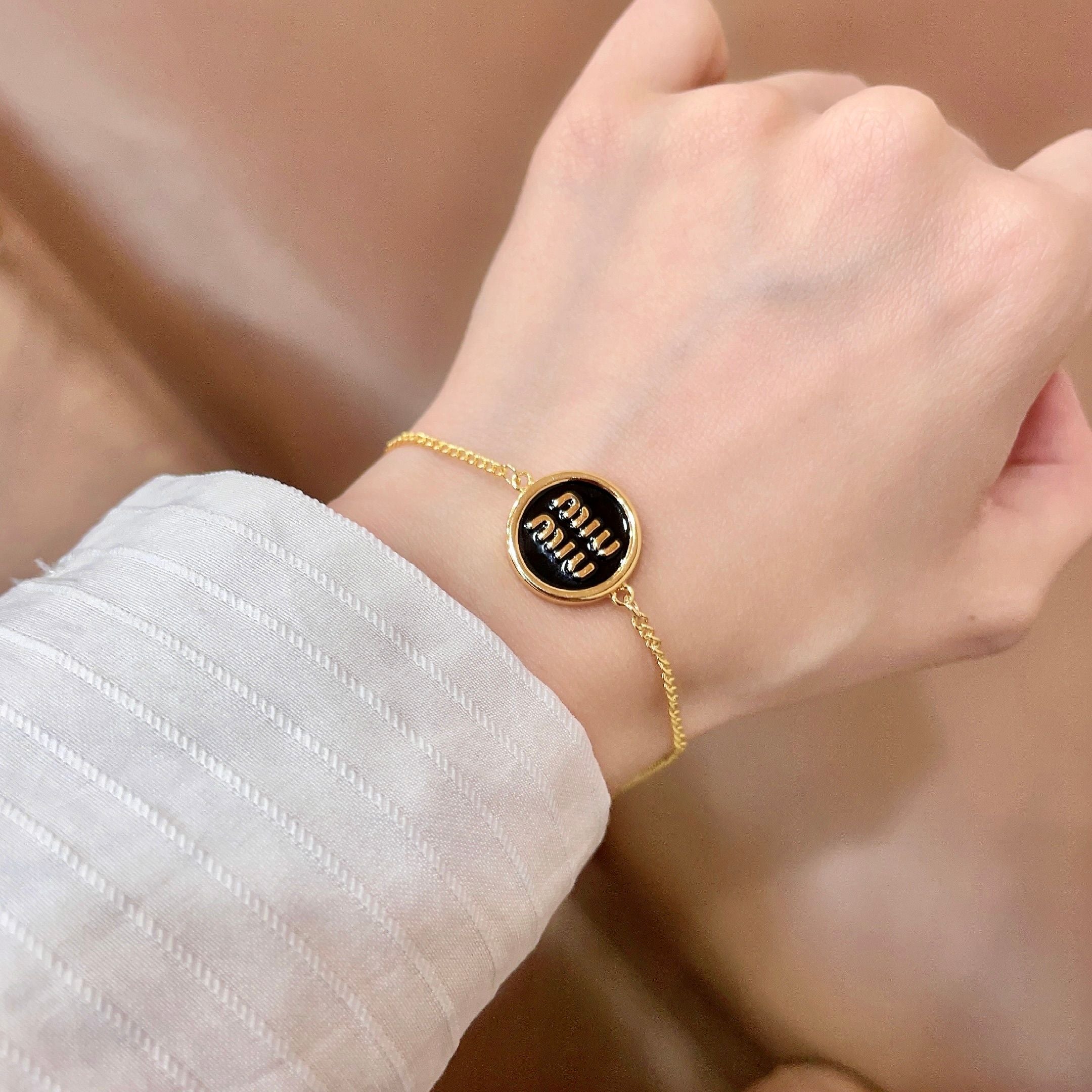 MIUMIU 26S LOGO ROUND BRACELET IN BLACK ENAMEL AND GOLD TONE METAL 631809