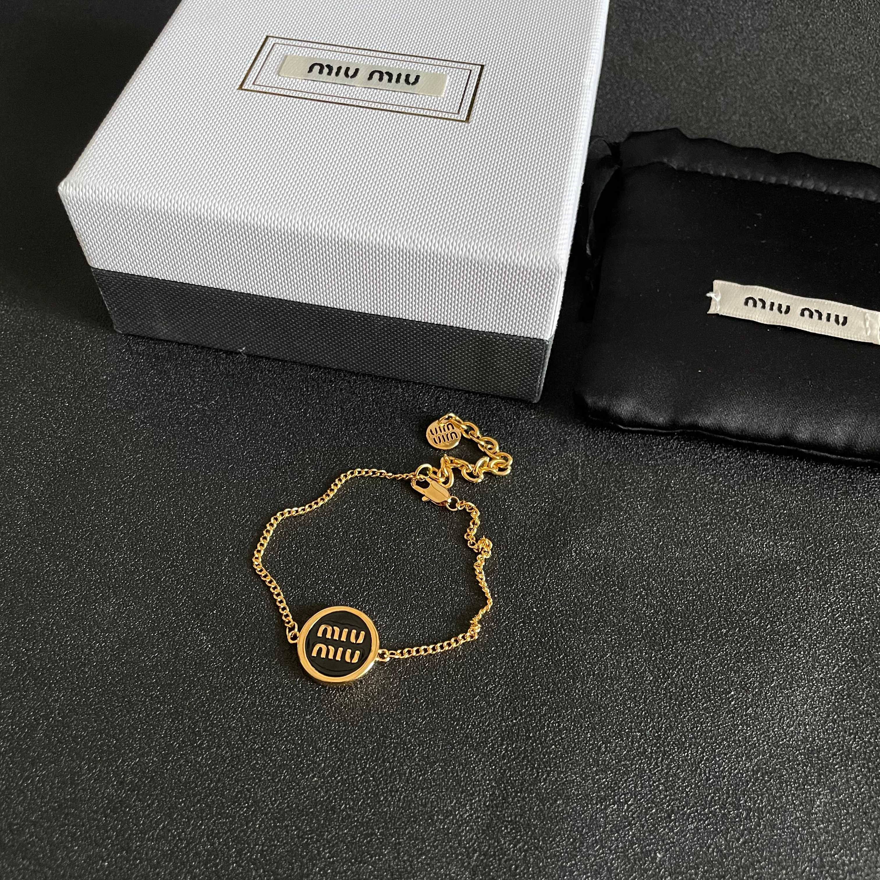 MIUMIU 26S LOGO ROUND BRACELET IN BLACK ENAMEL AND GOLD TONE METAL 631809