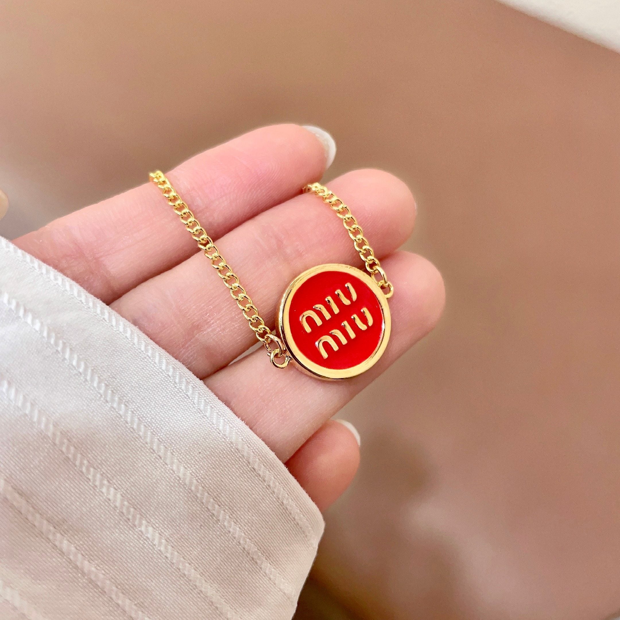 MIUMIU 26S LOGO ROUND BRACELET IN RED ENAMEL AND GOLD TONE METAL 631810