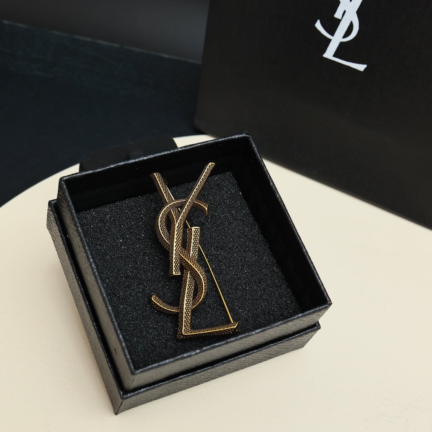 YSL 26S TEXTURED MONOGRAM BROOCH IN ANTIQUE GOLD TONE METAL