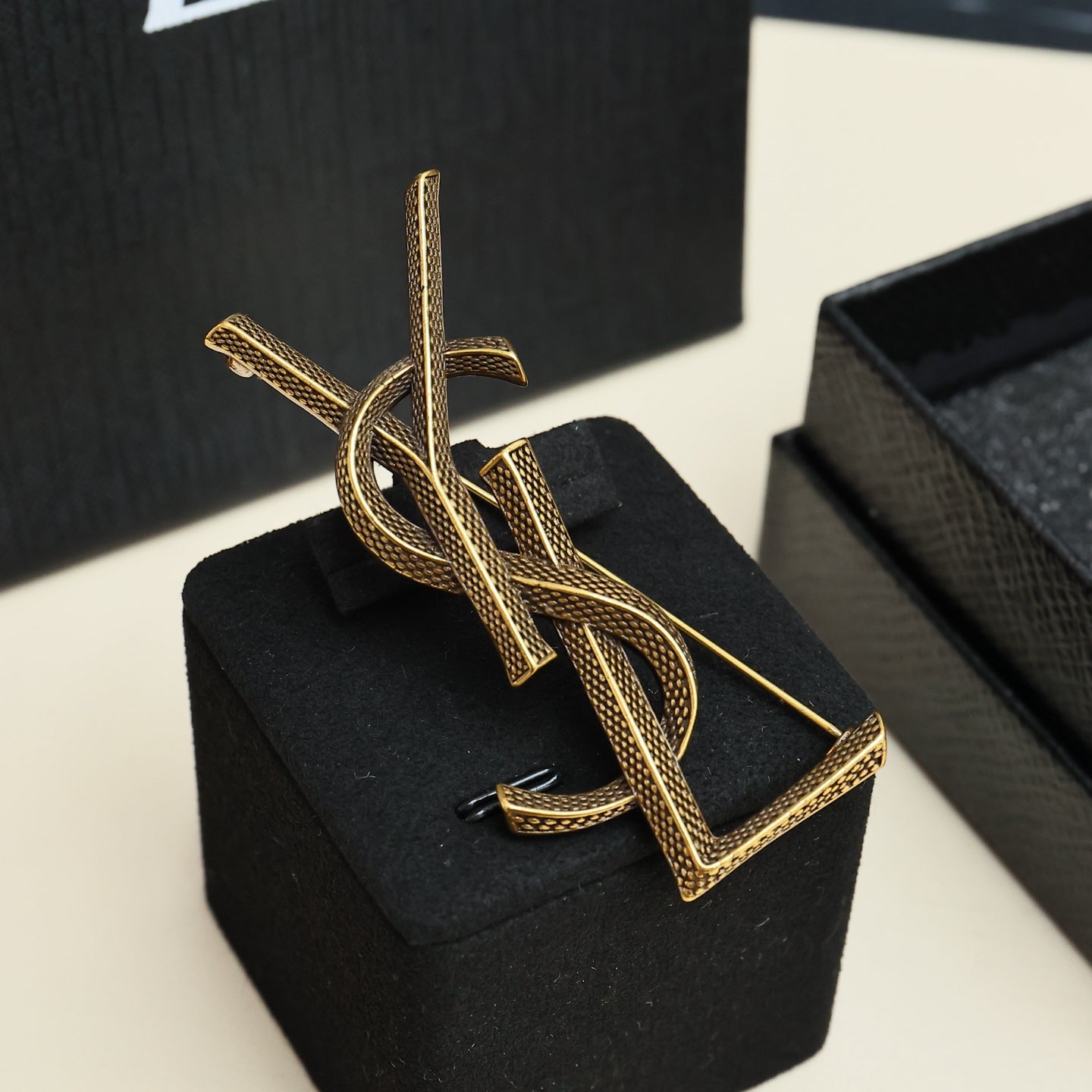 YSL 26S TEXTURED MONOGRAM BROOCH IN ANTIQUE GOLD TONE METAL