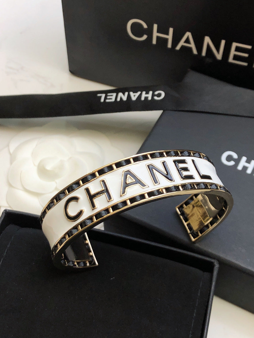CHANEL 26S CHANEL LOGO ENAMEL CUFF BRACELET WITH BLACK TRIM IN GOLD METAL 630835