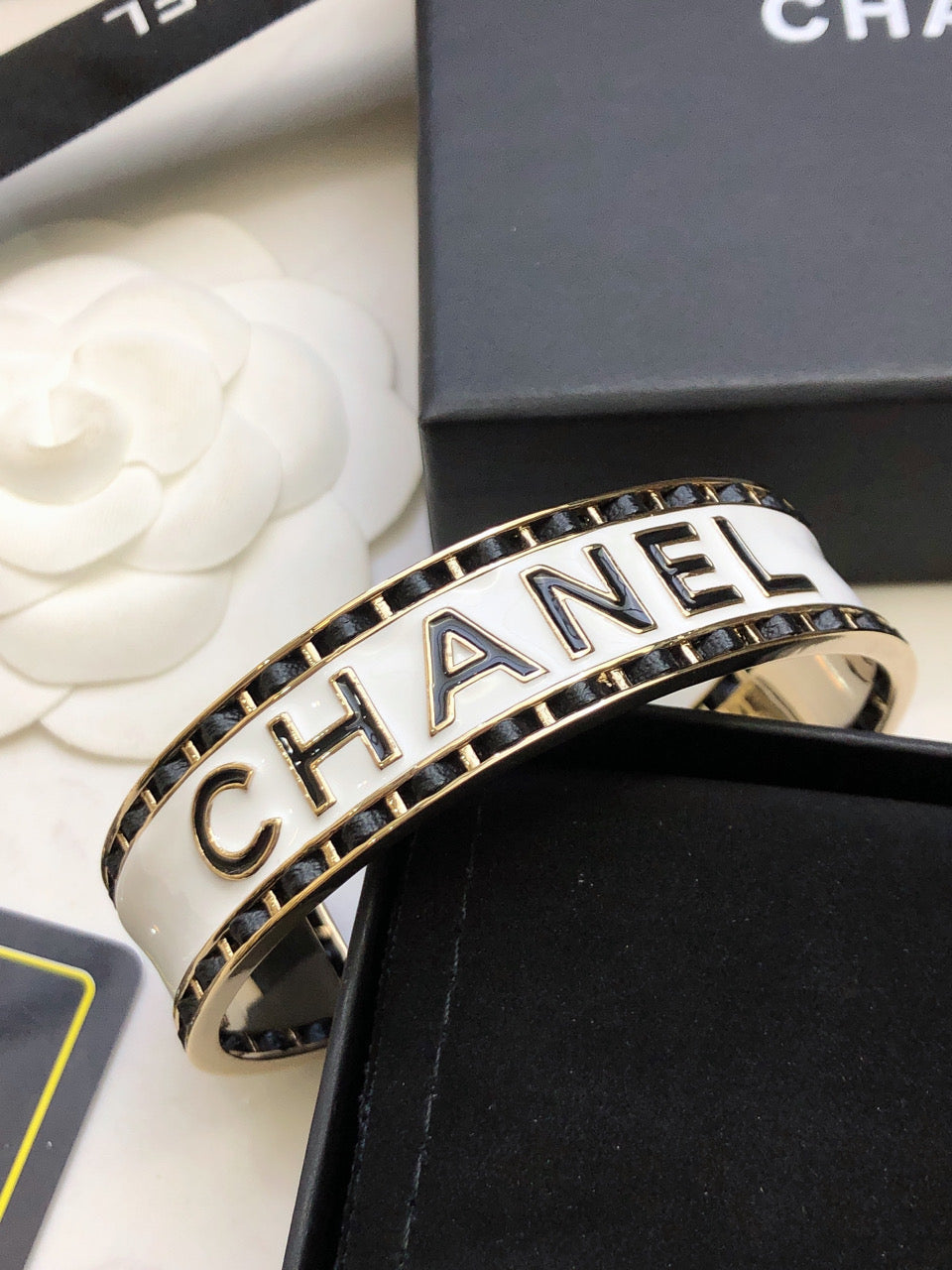 CHANEL 26S CHANEL LOGO ENAMEL CUFF BRACELET WITH BLACK TRIM IN GOLD METAL 630835