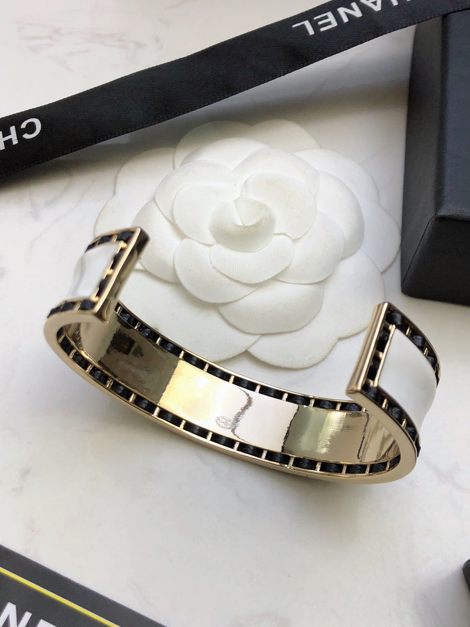 CHANEL 26S CHANEL LOGO ENAMEL CUFF BRACELET WITH BLACK TRIM IN GOLD METAL 630835